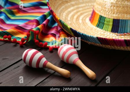 Cappello sombrero messicano, maracas e poncho colorato su sfondo di legno Foto Stock