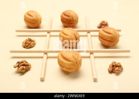 Gioco TIC tac con noci e biscotti su sfondo beige, primo piano Foto Stock