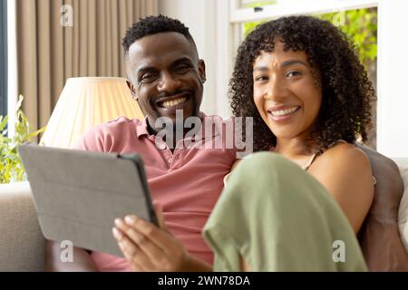 Una coppia afroamericana birazziale condivide un momento con un tablet a casa Foto Stock