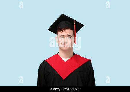 Studente laureato attento su sfondo blu Foto Stock