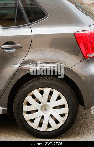 Un'auto con un parafango danneggiato è parcheggiata sul lato della strada Foto Stock