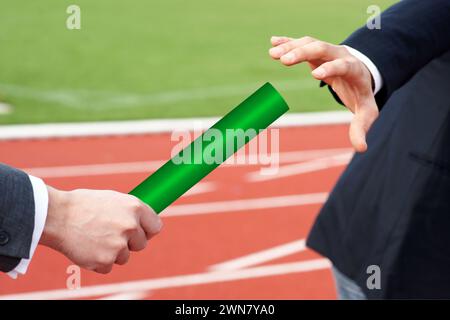 Uomo d'affari che passa il testimone verde alla successione di concept partner supporta il lavoro di squadra Foto Stock