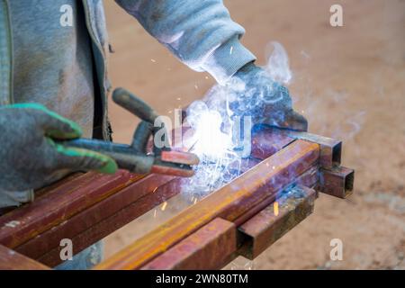 Saldatrice saldatura di due profili in ferro in cantiere in una giornata di sole Foto Stock