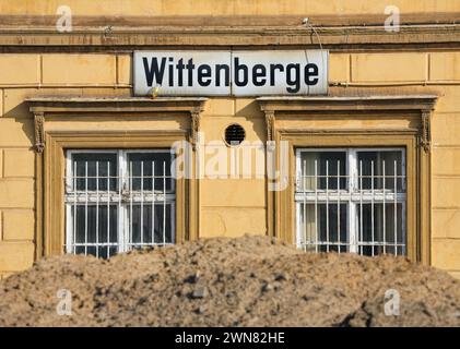 Wittenberge, Germania. 28 febbraio 2024. Un mucchio di sabbia si trova dietro una recinzione metallica di fronte all'edificio della stazione ferroviaria di Wittenberge. La città sull'Elba a Prignitz diventerà la sede della prima accademia cittadina tedesca. La Small Town Academy è una piattaforma di networking e conoscenza a livello nazionale per le piccole città in Germania. L'ufficio si sposterà nelle stanze dell'edificio storico della stazione ferroviaria, che è attualmente in fase di ristrutturazione. Credito: Soeren Stache/dpa/Alamy Live News Foto Stock