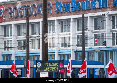 Rostock, Germania. 1 marzo 2024. Di fronte al deposito chiuso di Rostocker Straßenbahn AG ( RSAG) è appeso uno striscione con la scritta "investire nel personale". Venerdì, Verdi organizza uno sciopero di avvertimento sui trasporti pubblici a livello nazionale in collaborazione con Fridays for Future con il motto #Wirfahrenzusammen. Crediti: Frank Hormann/dpa-Zentralbild/dpa/Alamy Live News Foto Stock