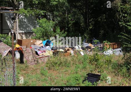 Un cortile pieno di spazzatura e spazzatura circondato da alberi Foto Stock