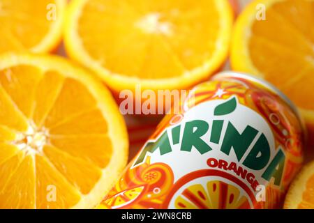 KIEV, UCRAINA - 7 LUGLIO 2023 bevanda all'arancia Mirinda con molte arance fresche su sfondo colorato Foto Stock