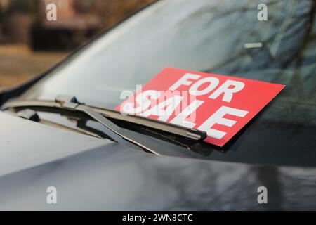 Cartello auto in vendita di fronte all'auto. Uomini che mettono la sua auto in vendita. Foto Stock