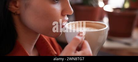 Bella donna attraente che beve caffè nel caffè, si rilassa, si fa una pausa caffè. Bevande e tempo libero Foto Stock