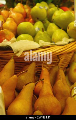 Le pere si trovano impilate sotto un cesto intrecciato in un mercato agricolo Foto Stock
