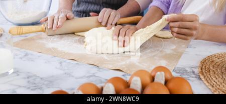 Madre che insegna alla figlia a preparare l'impasto usando farina e uova in cucina, a mani da vicino. Concetto di connettere generazioni di donne attraverso la cucina Foto Stock