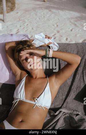 Giovane donna in un Beach club che prende il sole su un lettino Foto Stock