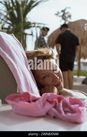 Giovane donna in un Beach club che prende il sole su un lettino Foto Stock