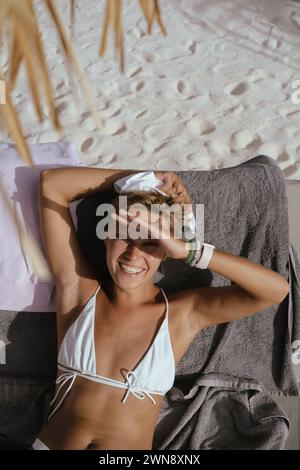 Giovane donna in un Beach club che prende il sole su un lettino Foto Stock