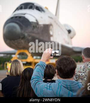 Un osservatore tiene in mano un dispositivo mobile per registrare lo Space Shuttle Atlantis mentre arriva alla nuova casa del Kennedy Space Center Visitor Complex, venerdì 2 novembre 2012, a Cape Canaveral, Flag. La navicella ha viaggiato per 125.935.769 miglia durante 33 voli spaziali, incluse 12 missioni alla stazione spaziale Internazionale. Il suo ultimo volo, STS-135, ha chiuso l'era del programma Space Shuttle con un atterraggio il 21 luglio 2011. Credito fotografico: (NASA/Bill Ingalls) Foto Stock