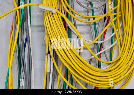 Vecchi cavi elettrici colorati appesi a una parete. Cavi a doppino intrecciato CAT5 per reti di computer. Foto Stock