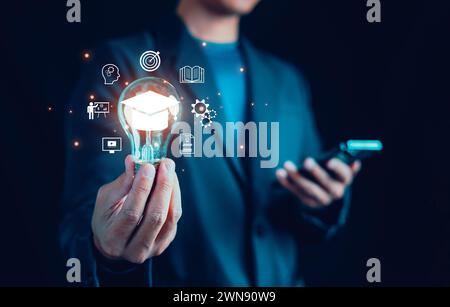 Mano di un uomo che mostra l'icona del cappello graduato nella lampadina, diploma, azienda, libro, conoscenza dello studio, corso di laurea in Internet, studente, insegnante, e-le Foto Stock