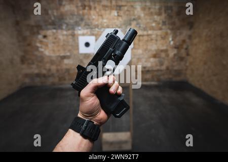 Tiro tattico da una pistola con puntino rosso sui bersagli in un poligono di tiro. Foto Stock