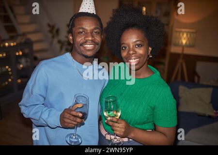 Ritratto in vita di una coppia afroamericana adulta che posa insieme per un ritratto tenendo un drink con flash Foto Stock