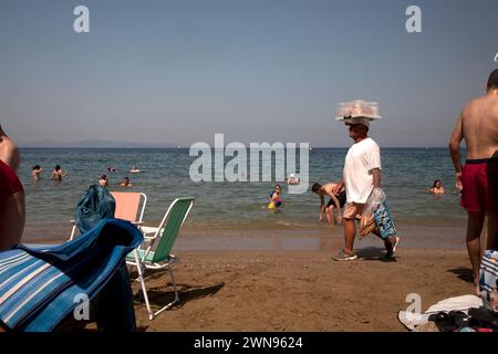 turisti e uomini che vendono cibo sulla spiaggia di vouliagmeni atene riviera grecia Foto Stock