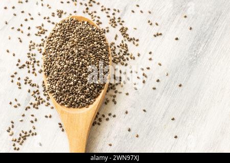 Semi di chia ( Salvia Hispanica ) in pala di legno o cucchiaio su fondo rustico. Cibo sano per i cereali Foto Stock