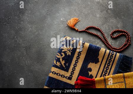 Tappeto di preghiera e rosario su sfondo di pietra per il culto nel mese del Ramadan Foto Stock