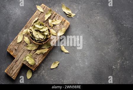 Foglie di alloro essiccate nel recipiente su fondo rustico, spezie ed erbe (Laurus nobilis) Foto Stock