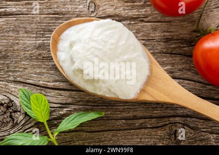 Yogurt fatto in casa con panna in un cucchiaio di legno, cibo sano Foto Stock