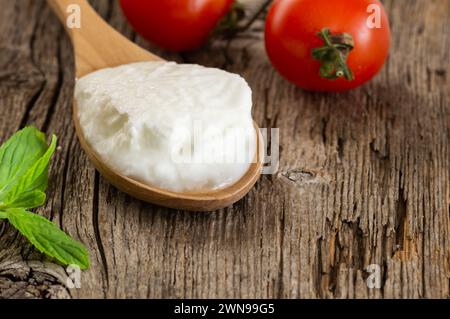 Yogurt fatto in casa con panna in un cucchiaio di legno, cibo sano Foto Stock