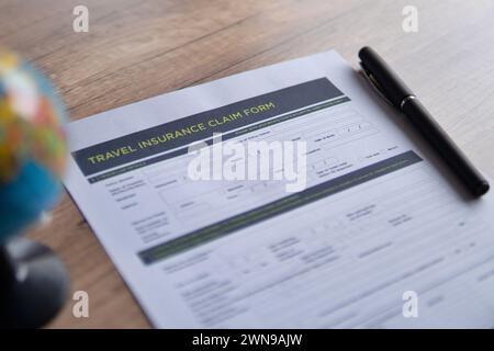 Immagine selettiva del modulo di richiesta dell'assicurazione di viaggio su un tavolo di legno. Concetto di viaggio, protezione e assicurazione. Foto Stock