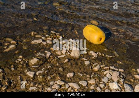 Primo piano di una grande boa gialla in polistirolo in acque poco profonde lungo la riva del fiume in Corea del Sud Foto Stock