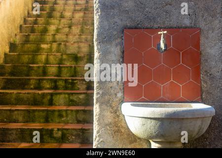 Un punto d'acqua in una casa provenzale, rubinetto, sole, estate, piastrelle calde, calde e rosse di alta qualità Foto Stock