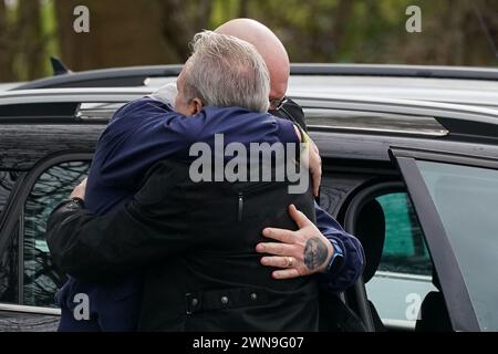 Il padre di Harry Dunn Tim Dunn e il patrigno Bruce Charles abbracciano mentre assistono al suo secondo funerale, al Banbury Crematorium nell'Oxfordshire, dopo aver trovato dei tessuti su alcuni vestiti quando la polizia ha restituito parte della sua moto e dei suoi vestiti più di quattro anni dopo essere rimasto ucciso in un incidente che coinvolgeva un dipendente del Dipartimento di Stato degli Stati Uniti. Data foto: Venerdì 1 marzo 2024. Foto Stock