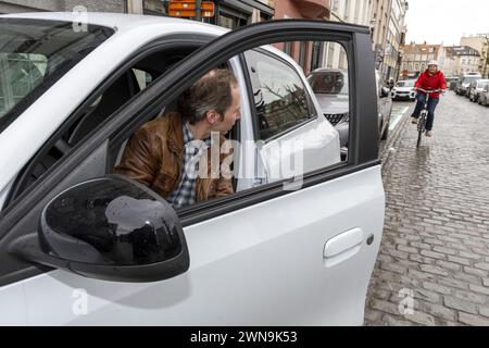 Un autista apre la porta della sua auto con il "Dutch Reach", mentre passa un ciclista, a Bruxelles, venerdì 1 marzo 2024. Il Parlamento europeo ha approvato una nuova norma per migliorare la sicurezza dei ciclisti. In futuro, ai conducenti verrà insegnato ad aprire la porta della vettura nel modo corretto. Il cosiddetto REACH olandese, che fa girare il conducente e guarda sullo specchietto retrovisore e sulle spalle, deve diventare lo standard in Europa per evitare incidenti con le porte aperte. BELGA FOTO NICOLAS MAETERLINCK BELGA FOTO NICOLAS MAETERLINCK Foto Stock