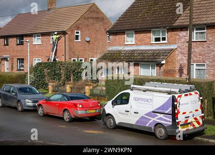 Lavoratore di British Telecom / BT OPENREACH, ingegnere delle telecomunicazioni in alto su fili di fissaggio su scala in una casa, nell'Hertfordshire, Inghilterra, Regno Unito Foto Stock