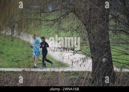 Rostock, Germania. 1 marzo 2024. I jogger corrono i loro giri nello stagno dei cigni a temperature pre-primaverili di 12 gradi Celsius. Oggi è l'inizio della primavera sul calendario. Crediti: Frank Hormann/dpa/Alamy Live News Foto Stock