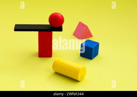 Sfera bilanciata su un trampolino circondata da altre figure geometriche Foto Stock