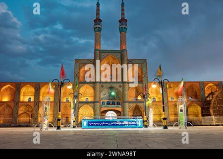 Takyeh (edificio dove i musulmani sciiti si riuniscono per piangere la morte di Husayn) e minareti del complesso Amir Chakhmaq illuminati di notte. Yazd, Iran. Foto Stock