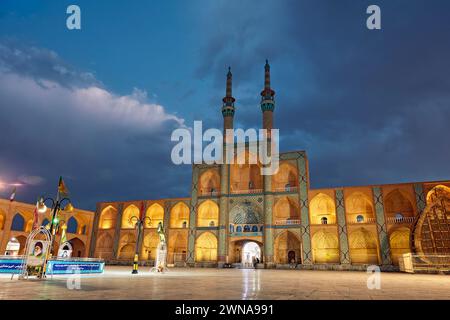 Takyeh (edificio dove i musulmani sciiti si riuniscono per piangere la morte di Husayn) e minareti del complesso Amir Chakhmaq illuminati di notte. Yazd, Iran. Foto Stock