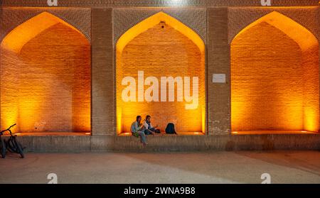 Due giovani ragazze iraniane si siedono insieme in un'alcova illuminata di notte. Città vecchia di Yazd, Iran. Foto Stock