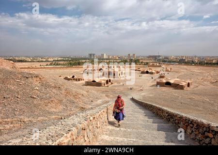 Una donna cammina su una scala di pietra fino alla Torre Zoroastriana del silenzio a Yazd, Iran. Gli zoroastriani credono che la terra, il fuoco e l'acqua siano elementi sacri a Foto Stock