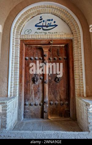 Vecchia porta d'ingresso in legno con due battitori separati - barra in metallo per uomini e anello in metallo per donne. Yazd, Iran. Foto Stock