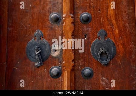 Dettaglio di una vecchia porta d'ingresso con due battitori separati - barra di metallo per uomini e anello di metallo per donne. Yazd, Iran. Foto Stock