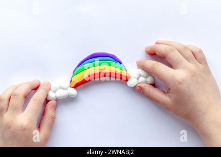 Il bambino scolpisce un arcobaleno e nuvole di plastilina. Creatività dei bambini Foto Stock