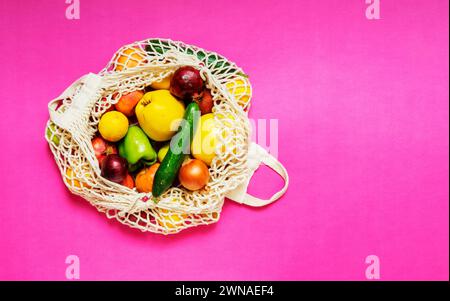 Borsa bianca con verdure e frutta diverse su sfondo rosa. Vista dall'alto Foto Stock