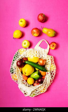 Sacchetto con spago bianco con verdure e frutta diverse su sfondo rosa. vista dall'alto. Foto Stock