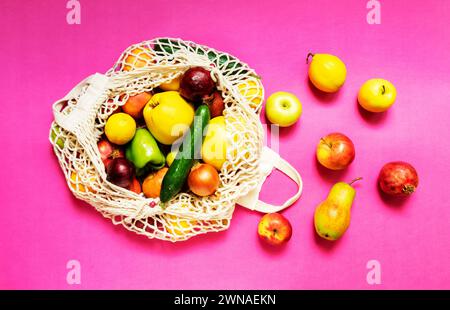 Sacchetto con spago bianco con verdure e frutta diverse su sfondo rosa. vista dall'alto. Foto Stock