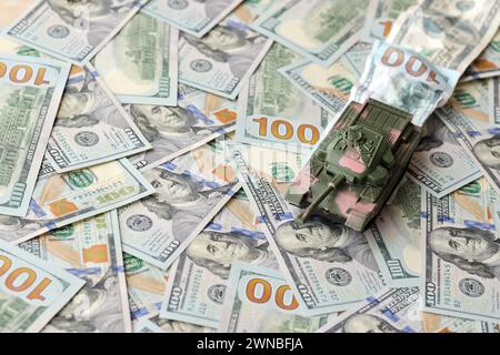 Carro armato su banconote da cento dollari schiacciate. Contesto del finanziamento di guerra e del prezzo di supporto militare per gli Stati Uniti d'America Foto Stock