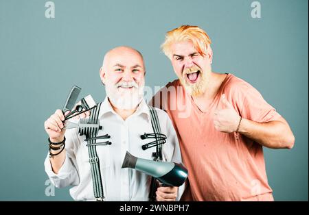 Barbiere facendo taglio di capelli di attraente uomo bearded in taglieri barbiere. Attrezzature per capelli. Barbiere con forbici e rasoio, barbiere. Barba uomo, maschio sopportato Foto Stock