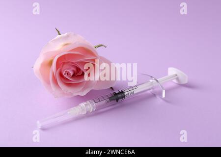 Cosmetologia. Siringa medica e fiore di rosa su sfondo viola Foto Stock